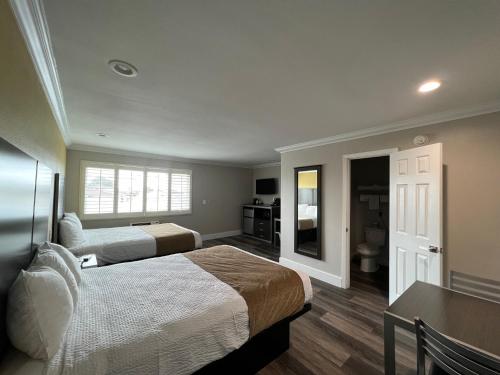 a hotel room with two beds and a bathroom at Deluxe Inn Hawthorne/ LAX in Hawthorne