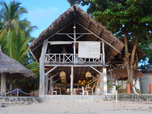 a hut on the beach with chairs and palm trees at Residence Casablanca in Ambatoloaka