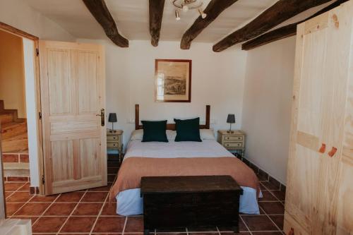 a bedroom with a large bed with green pillows at Casa de la Era, grande, de adobe, con patio y bodega in Fontanil de los Oteros