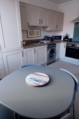 a white kitchen with a table and a stove at No 7 Quiet, two bedroom Ground Floor Flat in Tornagrain Great for early Airport departures or late flights in Dalcross