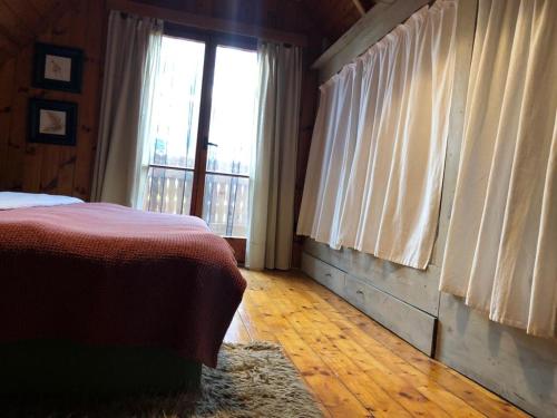 a bedroom with a bed and a large window at Wooden house in the nature in Modra