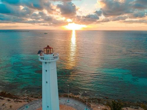 a lighthouse in front of the ocean with the sunset at Eco Cabañas Bluekay in Mahahual