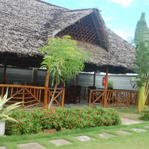 a restaurant with a thatched roof and a table at Joleen Safari Park in Dar es Salaam