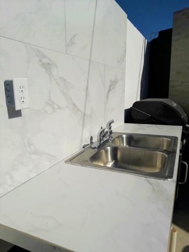 a kitchen counter with a sink in a white counter top at Santa Fé Apartamentos in Puerto Peñasco