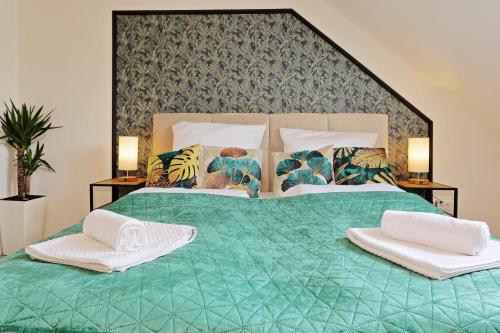 un grande letto verde con due asciugamani bianchi di NEAR MESSE! - Stay&Dream - 50qm - City - Kitchen - Netflix a Krefeld