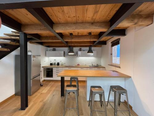 Il comprend une cuisine dotée de plafonds en bois, d'une table en bois et de tabourets. dans l'établissement duplex avec vue sur les arènes, à Arles