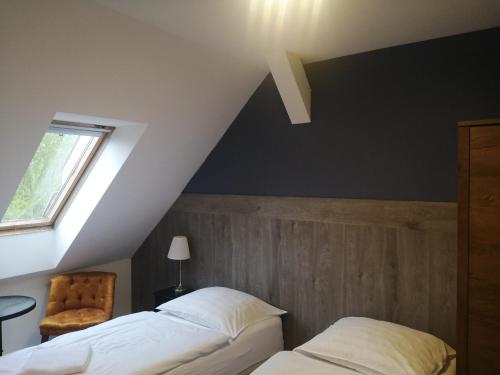 a attic bedroom with two beds and a chair at Filsdeger Ház - Central Rooms & Apartmans in Eger