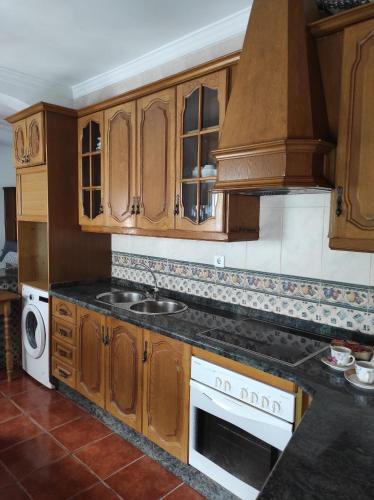 cocina con armarios de madera, fregadero y fogones en Casa Rural Moreno, en Setenil
