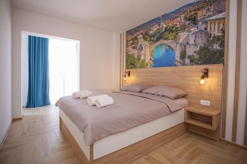 a bedroom with a large bed with a painting on the wall at Apartments & Rooms ARCH in Mostar