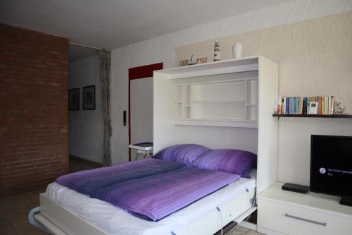 Cette chambre comprend un lit avec des draps violets et une télévision. dans l'établissement Appartment 2107 in Tossens, à Tossenserdeich
