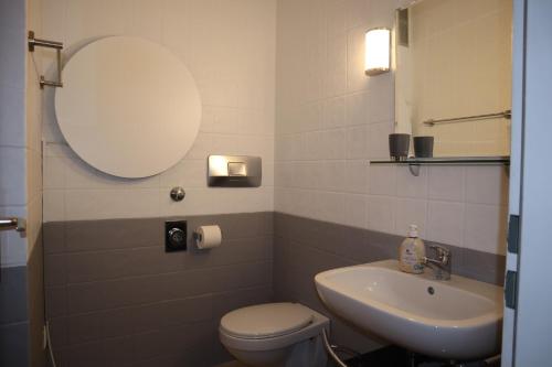a bathroom with a sink and a toilet and a mirror at Appartment 2107 in Tossens in Tossenserdeich
