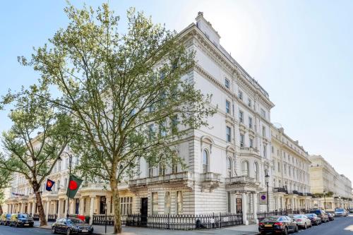 um edifício branco com carros estacionados em frente em Stunning Kensington apartment em Londres