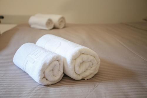 zwei Rollen weiße Handtücher auf einem Bett in der Unterkunft Apartments & Rooms ARCH in Mostar