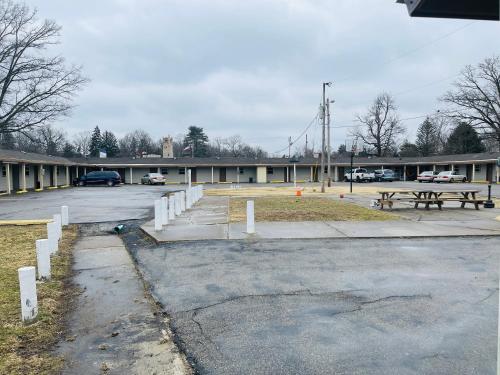 a parking lot with two picnic tables in front of a building at Woodridge Motel in Terre Haute