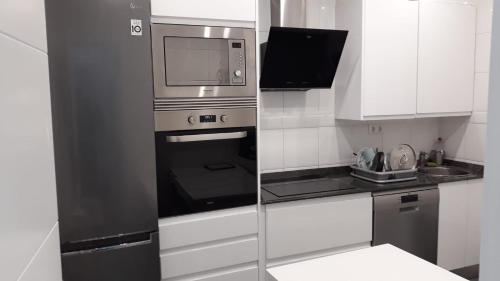 eine Küche mit einem Edelstahl-Backofen und einer Mikrowelle in der Unterkunft Amplio piso exterior en el centro de Santander in Santander