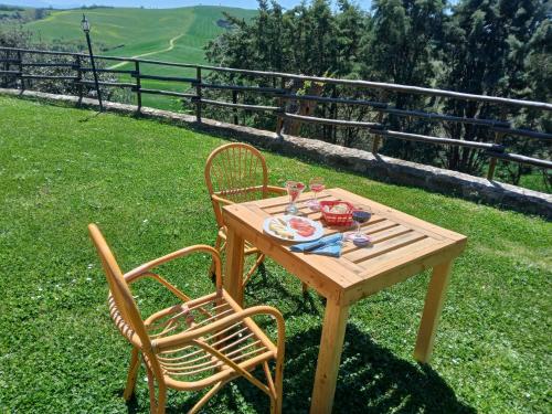 a wooden table with two chairs and a plate of food at Agriturismo Collesassi in Montalcino