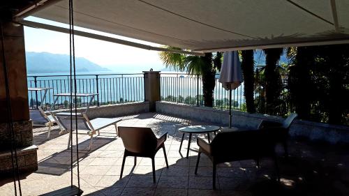 a balcony with chairs and tables and a view of the water at Sole & Lago-Lake in Maccagno con Pino e Veddasca