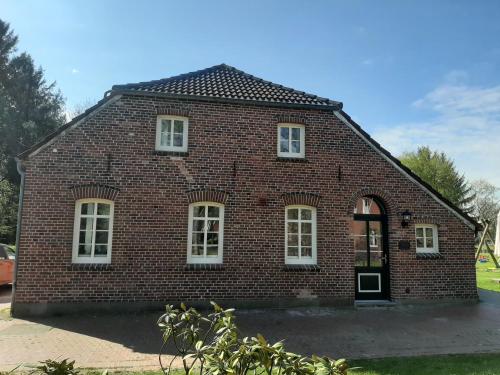 a red brick building with white windows and a door at Ferienwohnung Rendelchen in Großheide