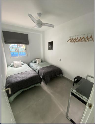 a bedroom with two beds and a ceiling fan at Morgan apartamentos Marbella centro in Marbella