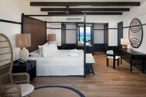 a bedroom with a white bed and a desk and a piano at Ocean Eden Bay - Adults Only - All Inclusive in Falmouth