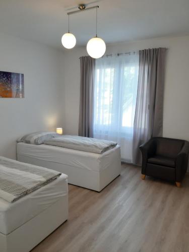 two beds in a bedroom with a chair and a window at Eisenstadt Apartments in Eisenstadt