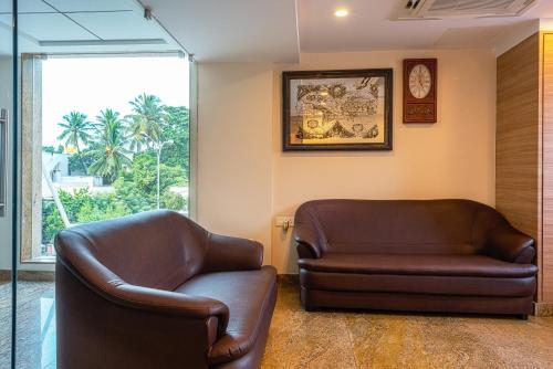 a living room with two leather chairs and a clock at Treebo Fourth Avenue in Chennai