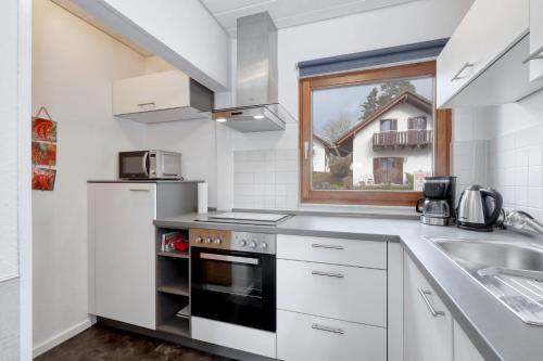 a white kitchen with a sink and a stove at Seepark Kirchheim Ferienhaus bei Zeta mit Sauna in Kirchheim