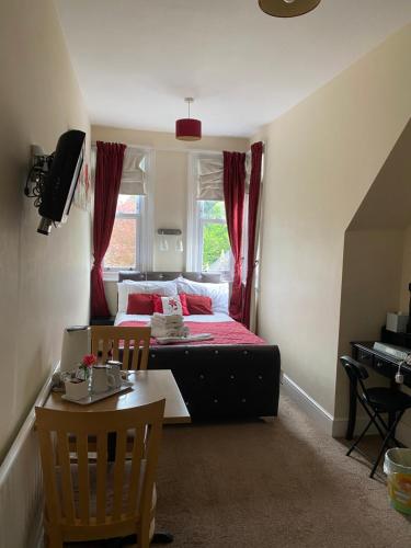 a bedroom with a bed with red curtains and a table at The Palms Guest house in Torquay