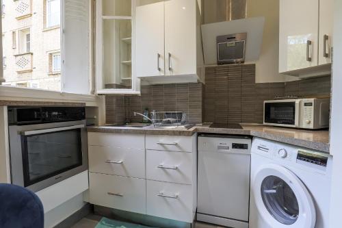 a kitchen with white cabinets and a washer and dryer at Studio Alésia - HALA PARIS in Paris