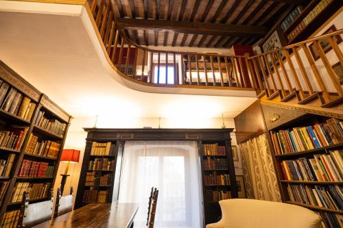 a library with a staircase and a table and books at Book and Bed in Orvieto