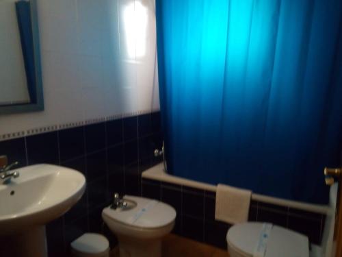 a bathroom with a sink and a toilet and a blue shower curtain at Hotel Restaurante Comendador Añon de Moncayo in Añón