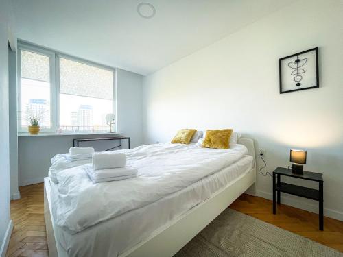 a white bedroom with a large bed with white sheets at COCO Apartments Jagiellońska 10 in Gdańsk