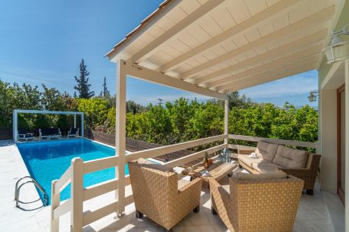 a patio with a table and chairs next to a swimming pool at SUN VILLA GLYFADA in Glyfada Fokidas