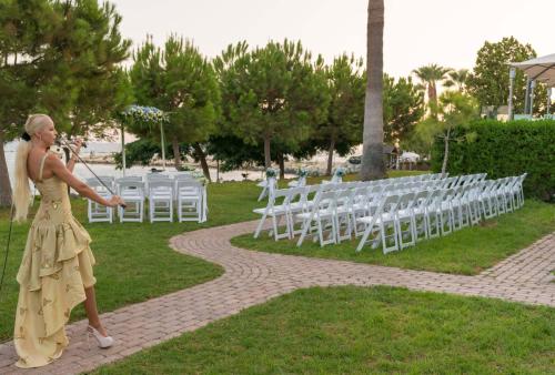a woman in a yellow dress pointing at a row of white chairs at Crowne Plaza Limassol by IHG in Limassol
