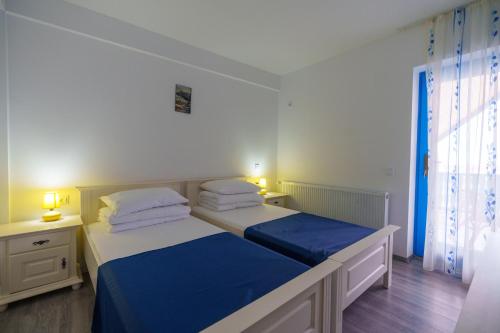 a bedroom with two beds with blue and white sheets at Pensiunea Dolosman in Jurilovca