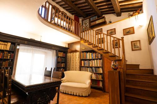 a room with a staircase with a chair and a table and books at Book and Bed in Orvieto