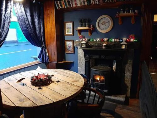 een eetkamer met een houten tafel en een open haard bij Gordon's Guesthouse in Loughrea