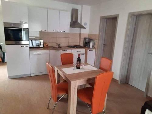 uma cozinha com uma mesa de madeira e cadeiras laranja em Apartman Tin em Vir