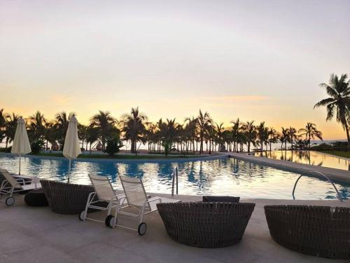 a large swimming pool with chairs and palm trees at Luxury 2 bedroom beach front at Nuevo Vallarta in Nuevo Vallarta