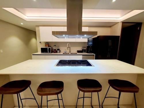 a kitchen with a counter with four bar stools at Luxury 2 bedroom beach front at Nuevo Vallarta in Nuevo Vallarta