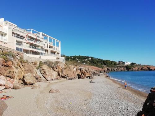 une plage avec un bâtiment sur le côté d'une falaise dans l'établissement Studio Cabine Sète Corniche Vue Mer, à Sète