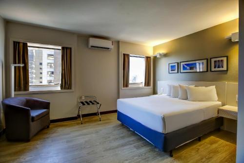 a hotel room with a bed and a chair at Comfort Suites Brasília in Brasília