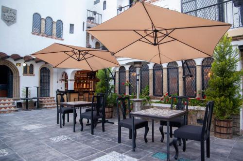 two tables and chairs with umbrellas on a patio at Hotel Boutique La Mansión Guadalajara in Guadalajara