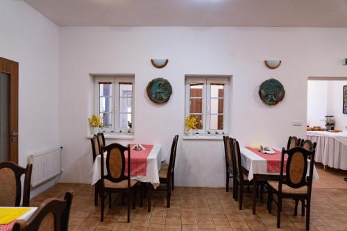 a dining room with tables and chairs and windows at Pension Florián in Pavlov