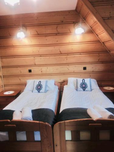 two beds in a room with wooden walls at Willa Tadeusz Zakopane in Zakopane