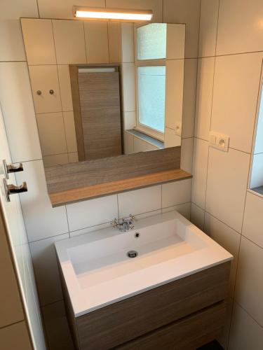 een badkamer met een wastafel en een spiegel bij De Lelie in Achel