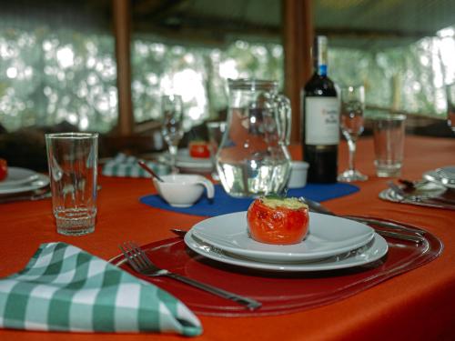einen Tisch mit einem Teller mit einer Tomate drauf in der Unterkunft Birdwatchers House y Lodge in Mindo