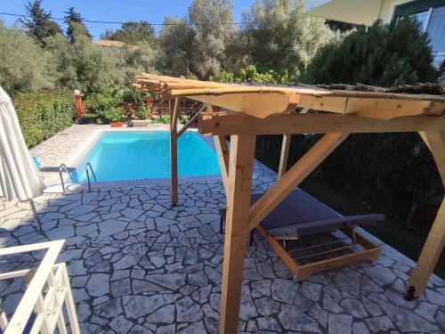a wooden picnic table next to a swimming pool at Villa Loula google it in Lygia