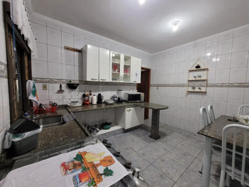 una cucina con pareti bianche piastrellate e armadi bianchi di Casa Grande para Família e Amigos a São Lourenço