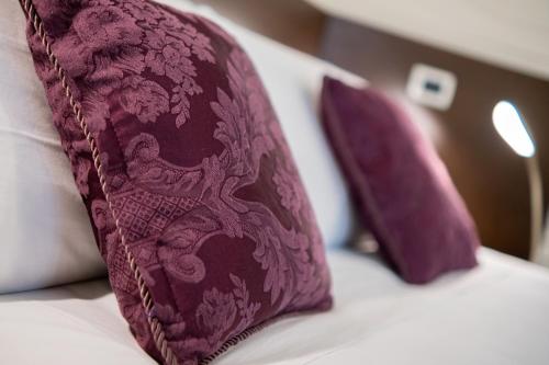two purple pillows sitting on top of a bed at Casa di Carlo Goldoni - Dimora Storica in Chioggia